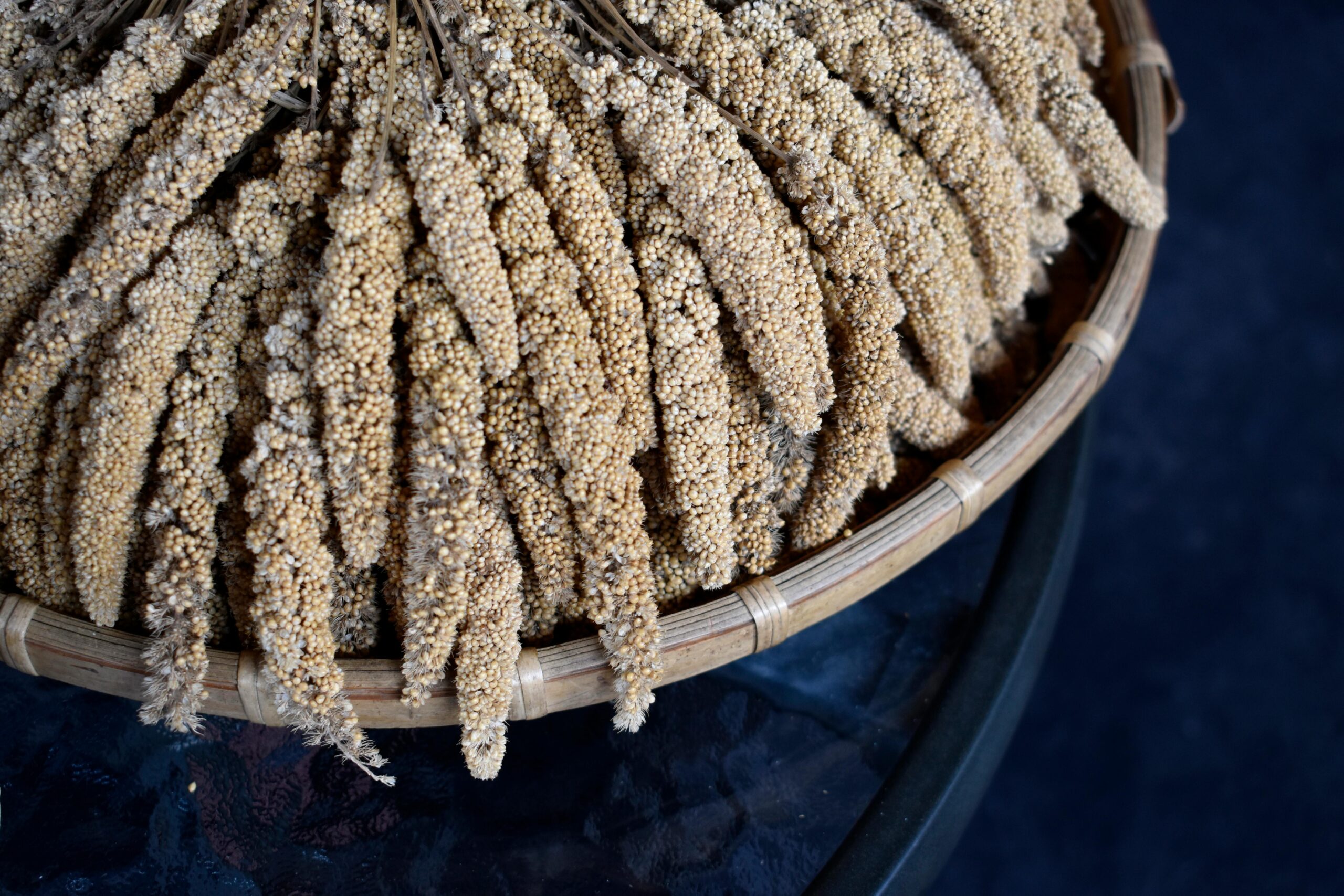 Detailed view of millet sticks artistically arranged in a bamboo winnower basket.